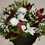 Dans un panier carré, chêne d'Amérique et aucuba structurent une composition de fleurs variées.