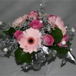 Dans une coupe en verre, germinis rose pastel et roses .