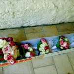 Bouquet rond de grosses roses pour la mariée et bouquets assortis de roses pour les petites filles du cortège.