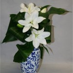 Le jeu de feuilles et le bleu du vase mettent valeur les fleurons de lilium épanouis.