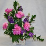 Giroflées mauves et pivoines roses dessinent un bouquet asymétrique dont le coeur est souligné d'hostas.