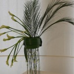 Mousson : arums et petites palmes areca sur un pied en plexiglass.