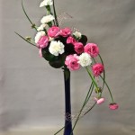 En rose et blanc,  renoncules et oeillets sur une élégante flûte bleue.