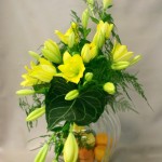 Gerbe de liliums jaune citron sur opulent vase en verre côtelé composent un bouquet de buffet estival.